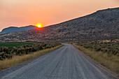 USA, Idaho, Bellevue, Dirt road and hills at sunset