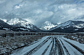 USA, Idaho, Stanley, Straße zwischen Weiden in verschneiter Berglandschaft
