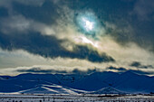 USA, Idaho, Bellevue, Sonne scheint durch die Wolken über schneebedeckten Bergen