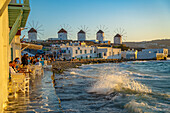 View of the windmills and crashing waves in Mykonos Town at sunset, Mykonos, Cyclades Islands, Greek Islands, Aegean Sea, Greece, Europe