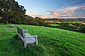 Wooden bench looking over green field countryside of High Weald on summer evening, Burwash, East Sussex, England, United Kingdom, Europe