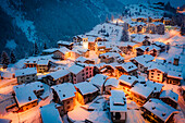Weihnachtsbeleuchtung auf Berghäusern und Chalets, die in der Abenddämmerung mit Schnee bedeckt sind, Pianazzo, Madesimo, Valle Spluga, Veltlin, Lombardei, Italien, Europa