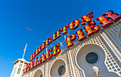 Blick auf Gleitschirm und Zeichen an einem sonnigen Tag am Brighton Palace Pier, Brighton, East Sussex, England, Vereinigtes Königreich, Europa