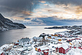 Luftaufnahme von traditionellen Holzhäusern, die im Winter mit Schnee bedeckt sind, Nusfjord, Nordland County, Lofoten-Inseln, Norwegen, Skandinavien, Europa