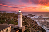 Aerial sea landscape view of Cape Tourinan Lighthouse at sunset with pink clouds, Galicia, Spain, Europe