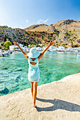 Cheerful woman with sun hat admiring the village of Loutro and crystal sea, Crete island, Greek Islands, Greece, Europe