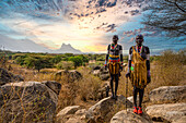 Traditionell gekleidete junge Mädchen aus dem Laarim-Stamm, die auf einem Felsen stehen, Boya Hills, Eastern Equatoria, Südsudan, Afrika