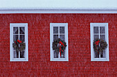 USA, Michigan, drei Weihnachtskränze in Schulhausfenstern bei Schneefall