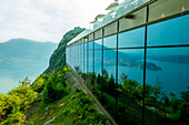 Hotel fünf Sterne Bürgenstock Resort mit Glasfassade mit Reflexion über den Vierwaldstättersee und die Berge bei Sonnenschein in Bürgenstock, Nidwalden, Schweiz.