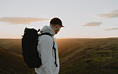 Male hiker with backpack on top of mountain at sunset, The Trinnacle, Derbyshire, England