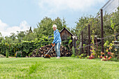 Woman trimming grass in sunny backyard\n