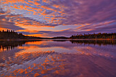 Kanada, Ontario, Distrikt Kenora. Waldherbstfarben spiegeln sich bei Sonnenaufgang auf dem Middle Lake wider