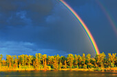 Canada, Yukon, Saskatchewan. Rainbow over forest and lake. Canada