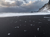 Küste bei Vik i Myrdal im Winter. Schwarzer vulkanischer Strand mit den Seestapeln Reynisdrangar, Island.