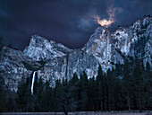 USA, Kalifornien, Yosemite-Nationalpark, Vollmond erhebt sich über Bridalveil Fall und Cathedral Rocks