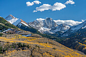 USA, Colorado. White River National Forest, Aspen und immergrüner Wald im Herbst unterhalb von Mt. Daly (links) und Capitol Peak (Mitte) mit Neuschnee auf den Gipfeln.