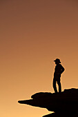 Mann, der auf einem Felsen steht und die Aussicht überblickt. (HERR)