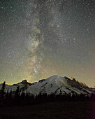 The lights of climbers can be seen on the mountain as the Milky Way rises behind Mt. Rainier, Mt. Rainier National Park, Washington State.