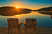 Kanada, Ontario, Temagami. Muskoka Stühle auf Snake Island Lake Dock bei Sonnenaufgang.