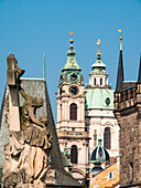 Europa, Tschechische Republik, Prag. Statue auf der Karlsbrücke und die St. Nikolaus-Kirche und Uhrturm und Türme der Altstadt.