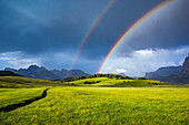 Italy, Dolomites, Alpi di Siusi. Double rainbow over mountain meadow.