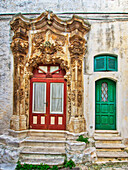 Italien, Apulien, Brindisi, Itria-Tal, Ostuni. Eine grüne und eine rote Tür, umgeben von kunstvollen Schnitzereien in den Straßen und Gassen der Altstadt von Ostuni.