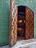 Italien, Toskana. Schöne Holztüren, die zu einem Fassraum in einem Weingut führen.
