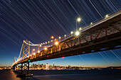 USA, California, San Francisco. Composite of star trails above Bay Bridge.