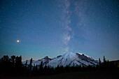 Die Lichter der Bergsteiger sind auf dem Berg zu sehen, während die Milchstraße hinter dem Mt. Rainier National Park, Washington State, aufgeht.
