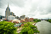 Downtown Nashville and the Cumberland river under a cloudy sky.