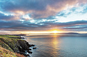 Sonnenaufgang über der Bucht von Dingle, während Fischerboote in der Grafschaft Kerry, Dingle, Irland, unterwegs sind