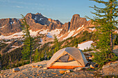 Backpacking tent at daybreak on ridge above Cutthroat Pass, near Pacific Crest trail. Cutthroat Peak is in the distance. North Cascades, Washington State