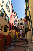 Touristen, Paar macht einen Spaziergang zwischen den bunten Häusern von Boccadasse, Genua, Ligurien, Italien.