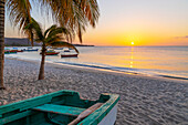 Caribbean, Grenada, Grenadines. Sunset and wooden fishing boat on Grand Anse Beach