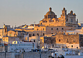 The picturesque old town of Ostuni in southern Italy, built on top of a hill and crowned by its Gothic Basilica or Cathedral at sunset.