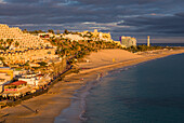 Spain, Canary Islands, Fuerteventura Island, Morro Jable, high angle view of Playa de la Cebada beach, sunset