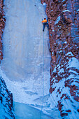 USA, Minnesota, Oberer See. Bergsteiger, der gefrorenen Wasserfall auf Klippe skaliert
