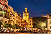 Restaurants auf dem Platz Plaza de San Francisco und der Glockenturm Giralda der Kathedrale Santa María de la Sede in der Abenddämmerung, Sevilla, Andalusien, Spanien