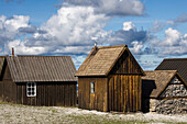 Small fishermen's huts stand close to each other. fleecy clouds. Faroe, Gotland, Sweden.