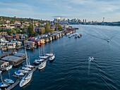 Aerial view of sailboats and houseboats on Lake Union with downtown Seattle in the background.