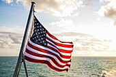 American flag waving in the wind, ocean in the background