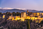 Blick vom Mirador de San Nicolas auf Alhambra und die schneebedeckten Berge der Sierra Nevada in der Abenddämmerung, Granada, Andalusien, Spanien