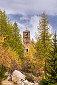 Zwischen den Bäumen sticht der Glockenturm einer Kirche hervor. Lys-Tal, Aostatal, Italien