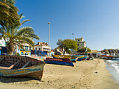 Traditionelle Fischerboote am Strand des Hafens, Wahrzeichen Torre de Belem im Hintergrund. Stadt Mindelo, eine Hafenstadt auf der Insel Sao Vicente, Kap Verde. Afrika