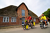 Brick buildings in Nieblum, cyclists on the island of Foehr, North Friesland, North Sea, Schleswig-Holstein, Germany, MR