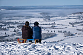 Wide view over the Königswinkel, in the foreground two people sitting on sleds, Buchenberg Alm, Allgäu Alps, Allgäu, Bavaria, Germany, Europe