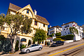 Seitenansicht eines Hauses an der sehr steile Hyde Street Straße mit Autos und Cable Car Schinen, San Francisco, Kalifornien, USA