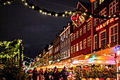Blick am Abend im Advent auf die historischen Haeuser und den Weihnachtsmarkt von Nyhavn in Kopenhagen, Dänemark, Winter