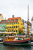 Old fishing cutter in front of the historic houses in Nyhavn, Copenhagen, Denmark