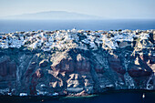 Aerial view of an island in the deep blue seas of the Aegean sea, rock formations, whitewashed houses perched on the cliffs.